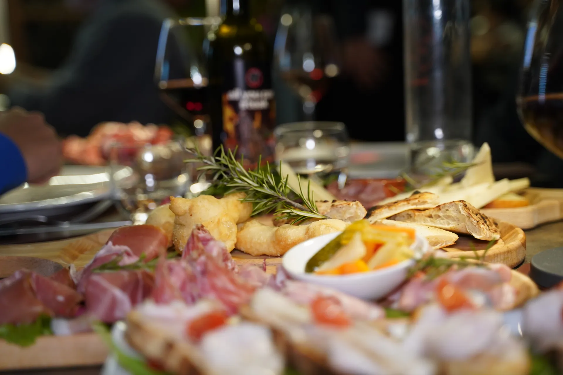 Tavola conviviale con taglieri di salumi, bruschette e vino rosso toscano